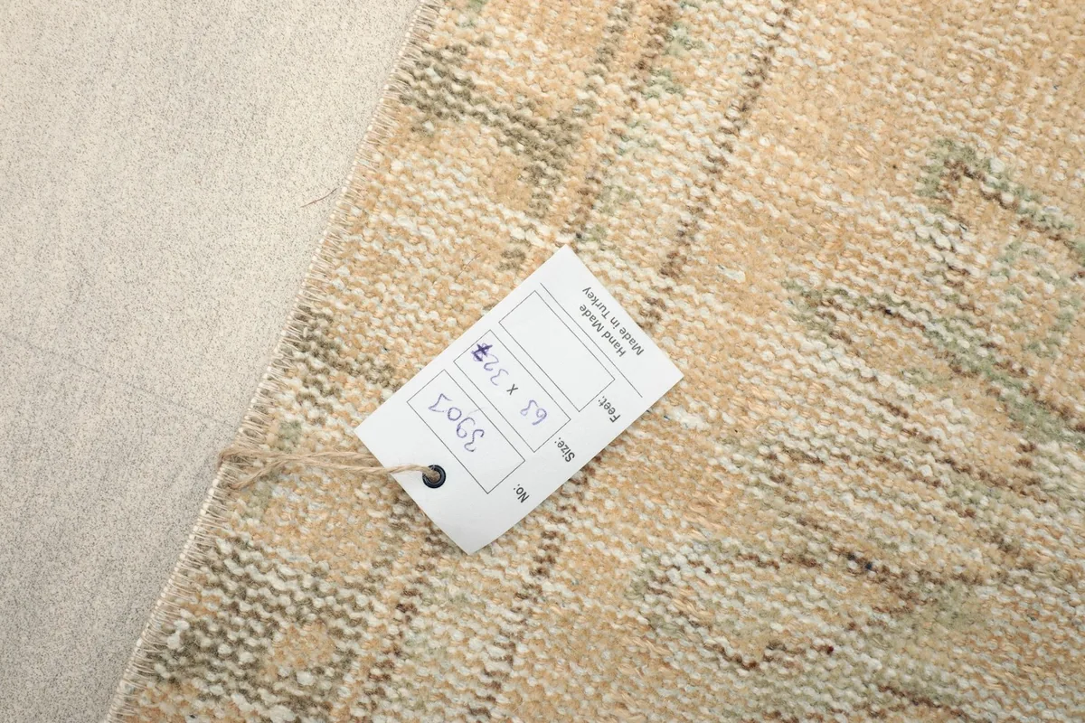 Close-up of the rug's label with size information (63 x 327 cm) and origin, attached to the back