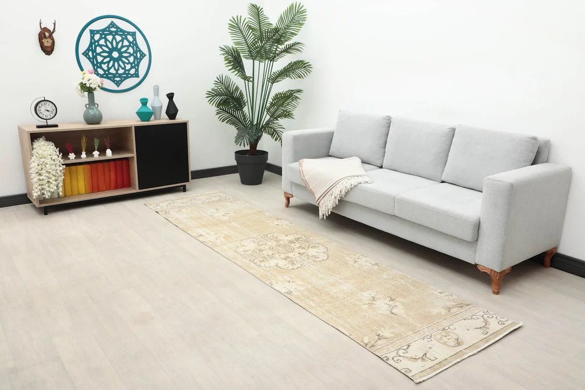 Overview of the beige runner rug in a modern living space with a sofa and plant, highlighting its scale.