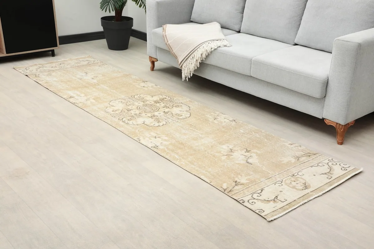 Angled view of the beige runner rug laid out in a room, showing its texture and pattern.