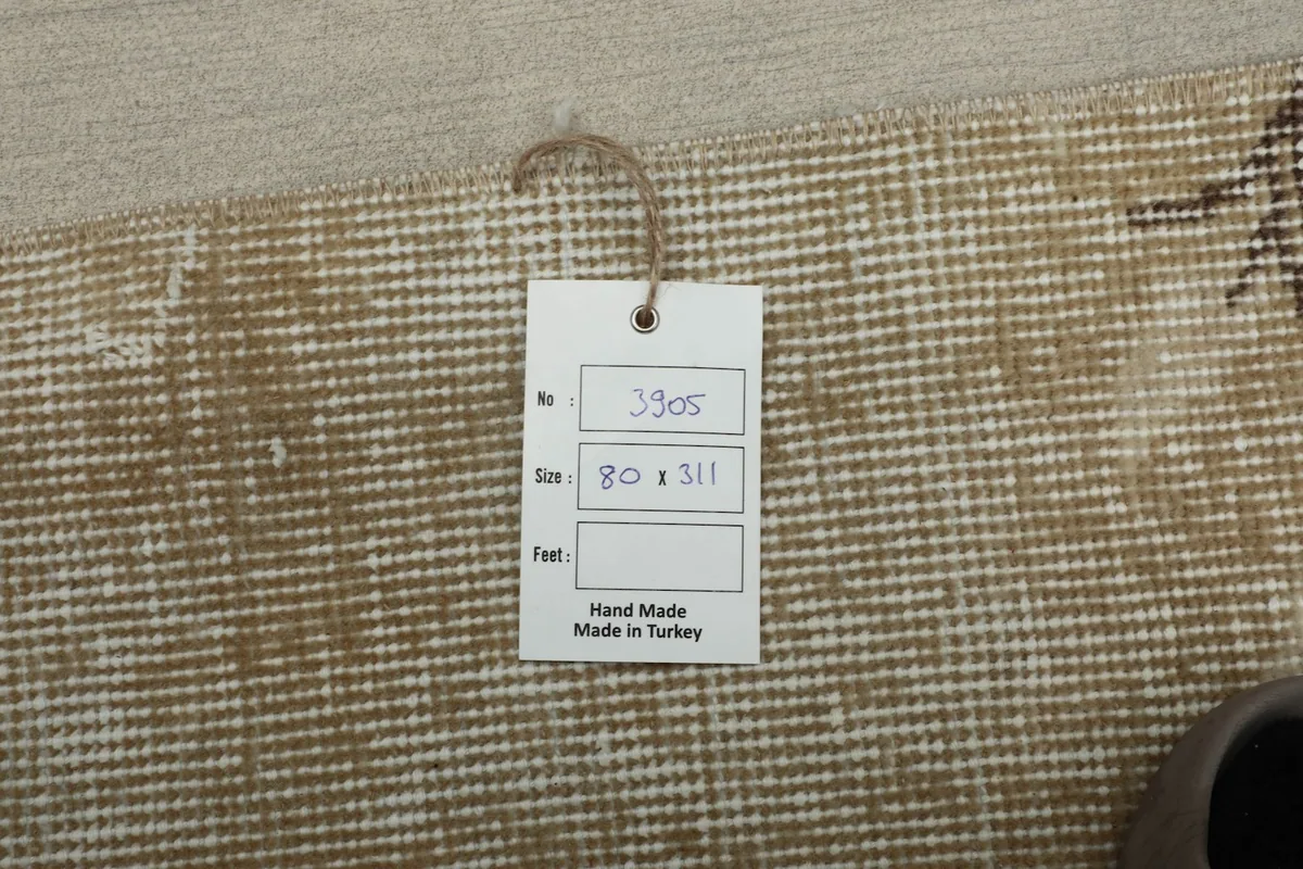 Close-up of the rug's back with a product tag showing 'Hand Made in Turkey' and dimensions.