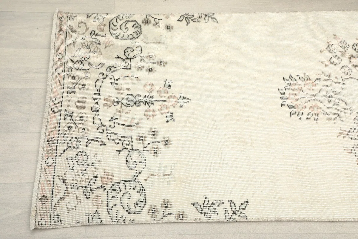 Detailed view of the intricate gray and rose floral motifs on the ivory runner