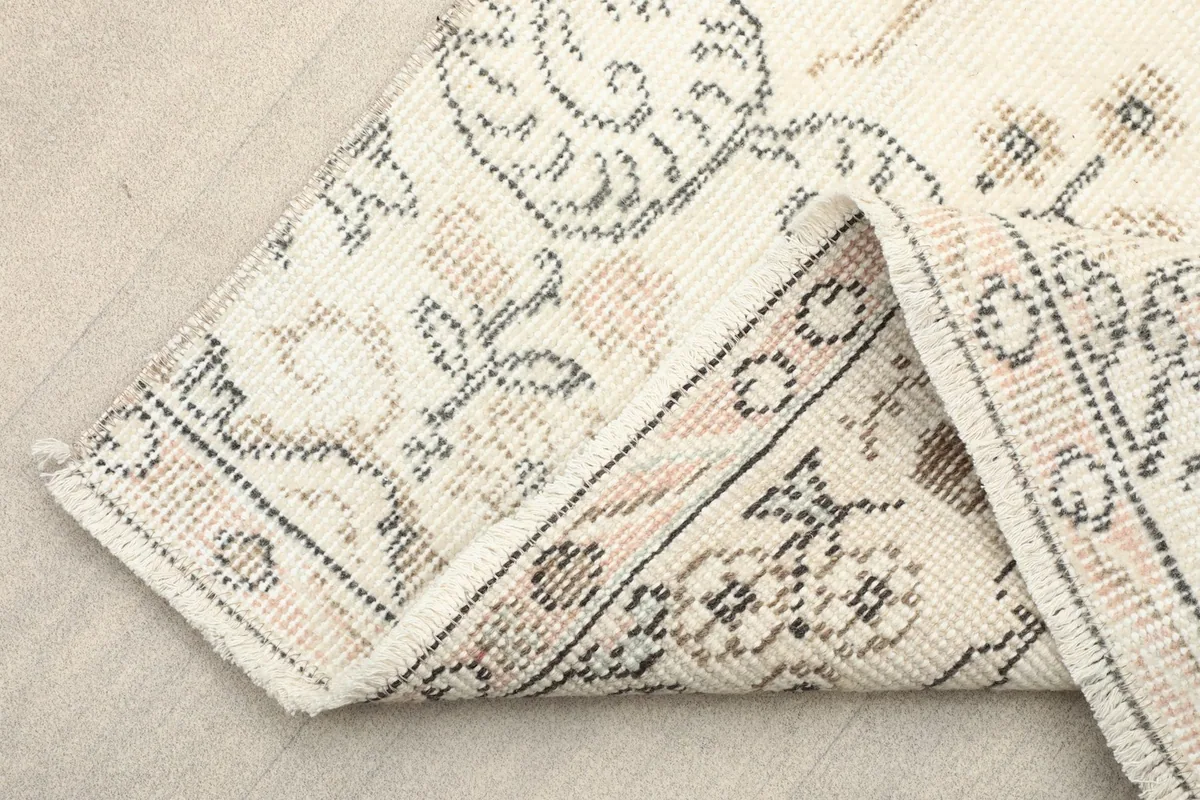 Folded corner showing the hand-knotted construction and fringe of the vintage rug