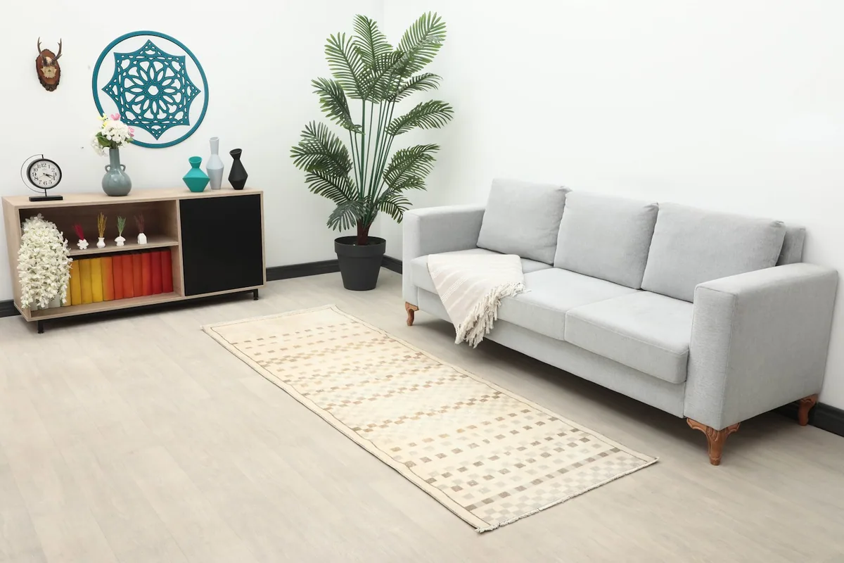 Beige and brown geometric runner in a living room setting, extending from a light gray sofa
