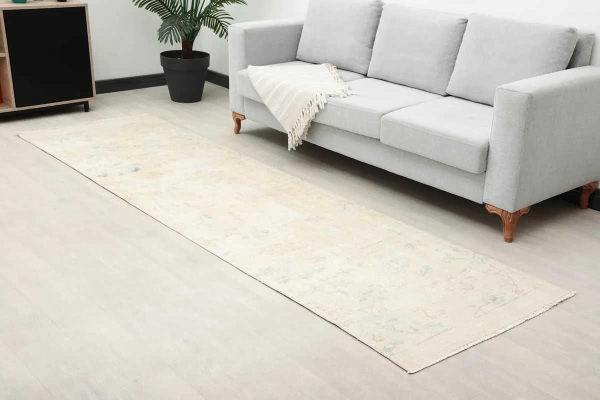 Angle view of the Anatolian runner rug on a light floor next to a gray sofa.