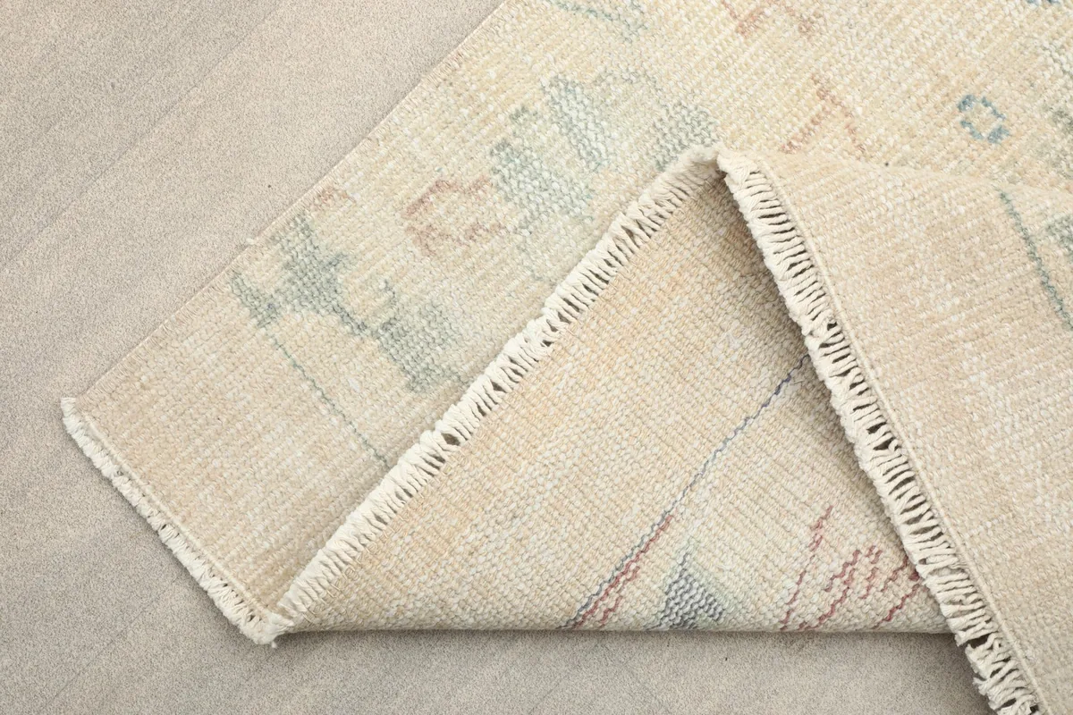 Corner of the rug folded to show the backside, demonstrating the hand-knotted construction.
