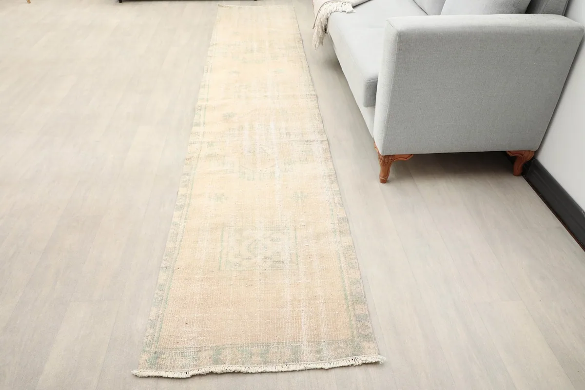 Vintage Anatolian runner rug laid out in a modern living space next to a light gray sofa.