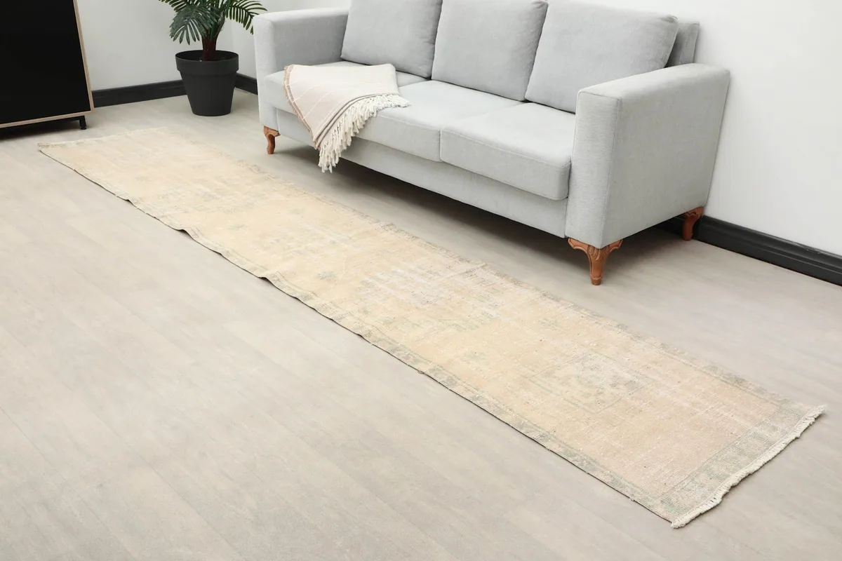 Overhead angle showing the full length of the runner rug in a room setting, highlighting its faded texture.