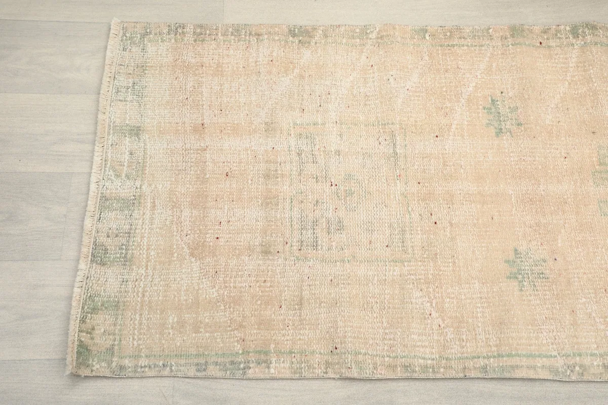Detailed section of the vintage runner rug, displaying the subtle border design and overall distressed look.