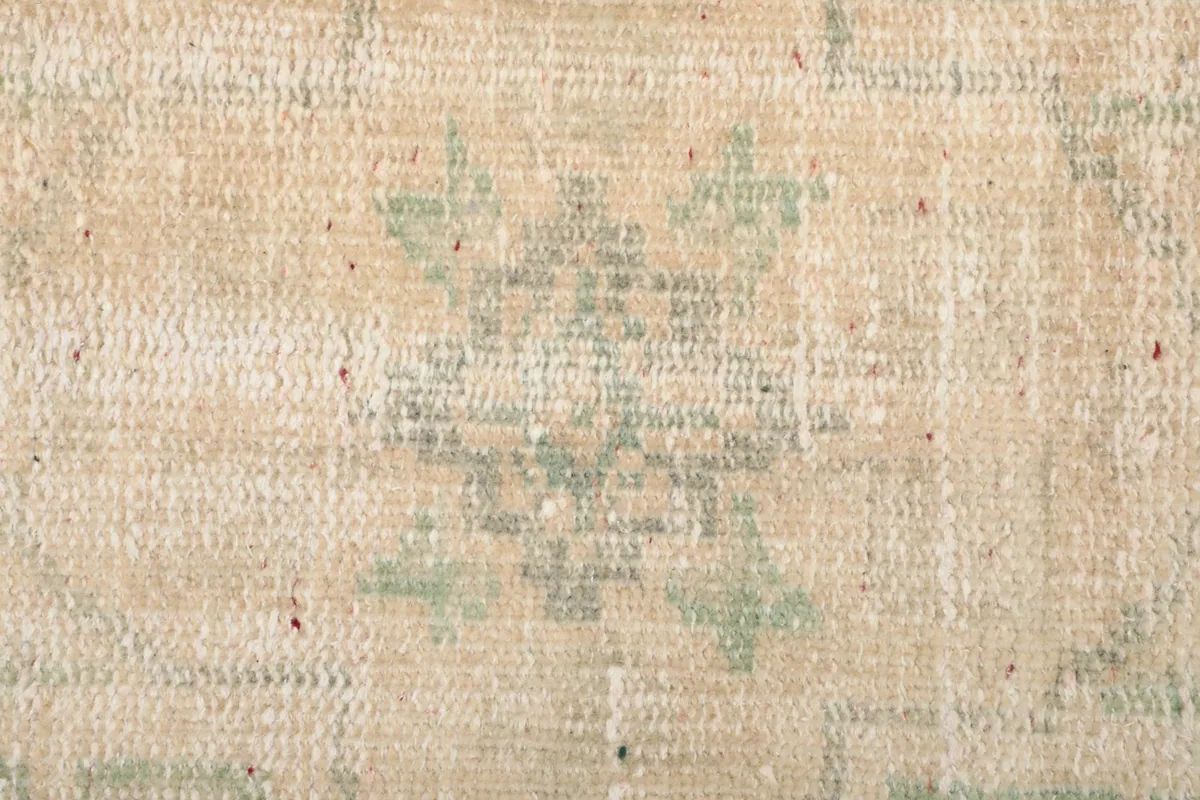 Close-up of a smaller geometric pattern element on the rug, showing variations in color and wear.