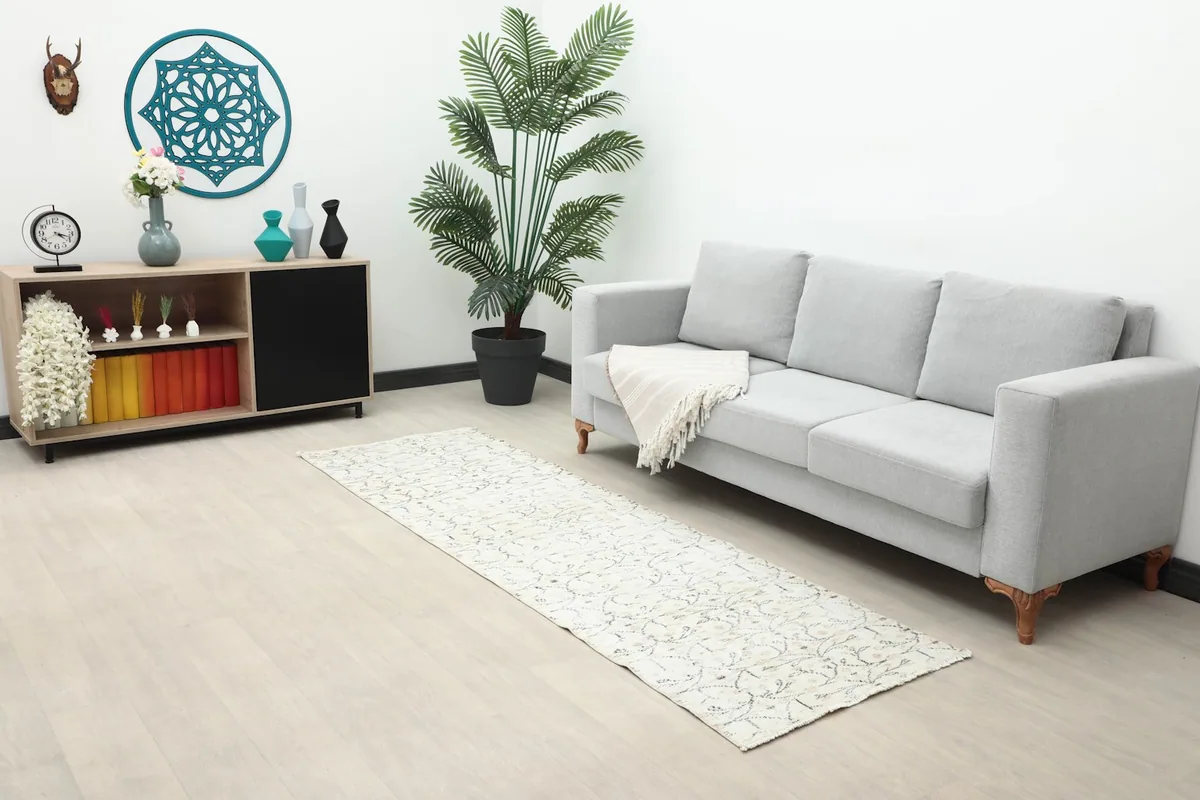 Wide shot of the ivory runner rug in a room with a gray sofa and wooden furniture, showcasing its scale.