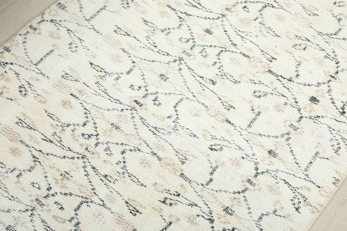 Detailed view of the hand-knotted texture and the intricate gray and tan botanical designs.