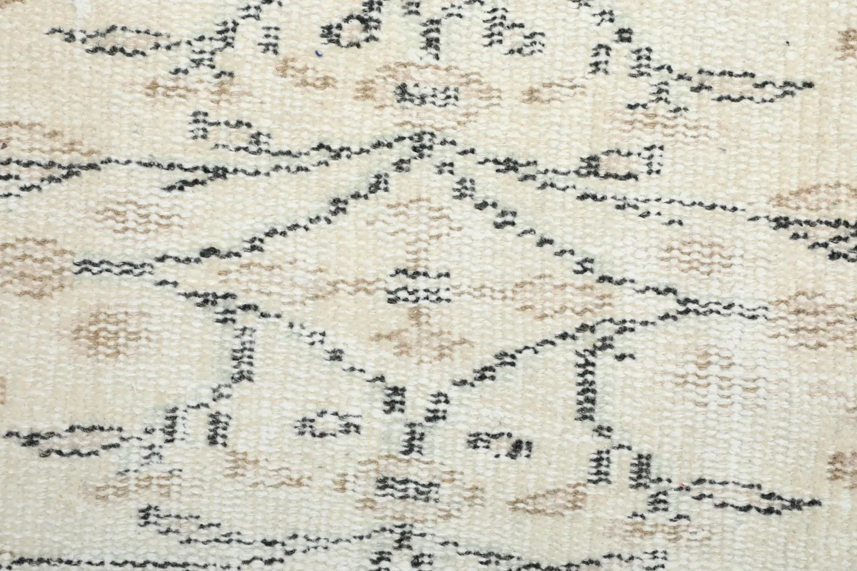 Extreme close-up showing the low wool pile and individual knots of the rug's pattern.