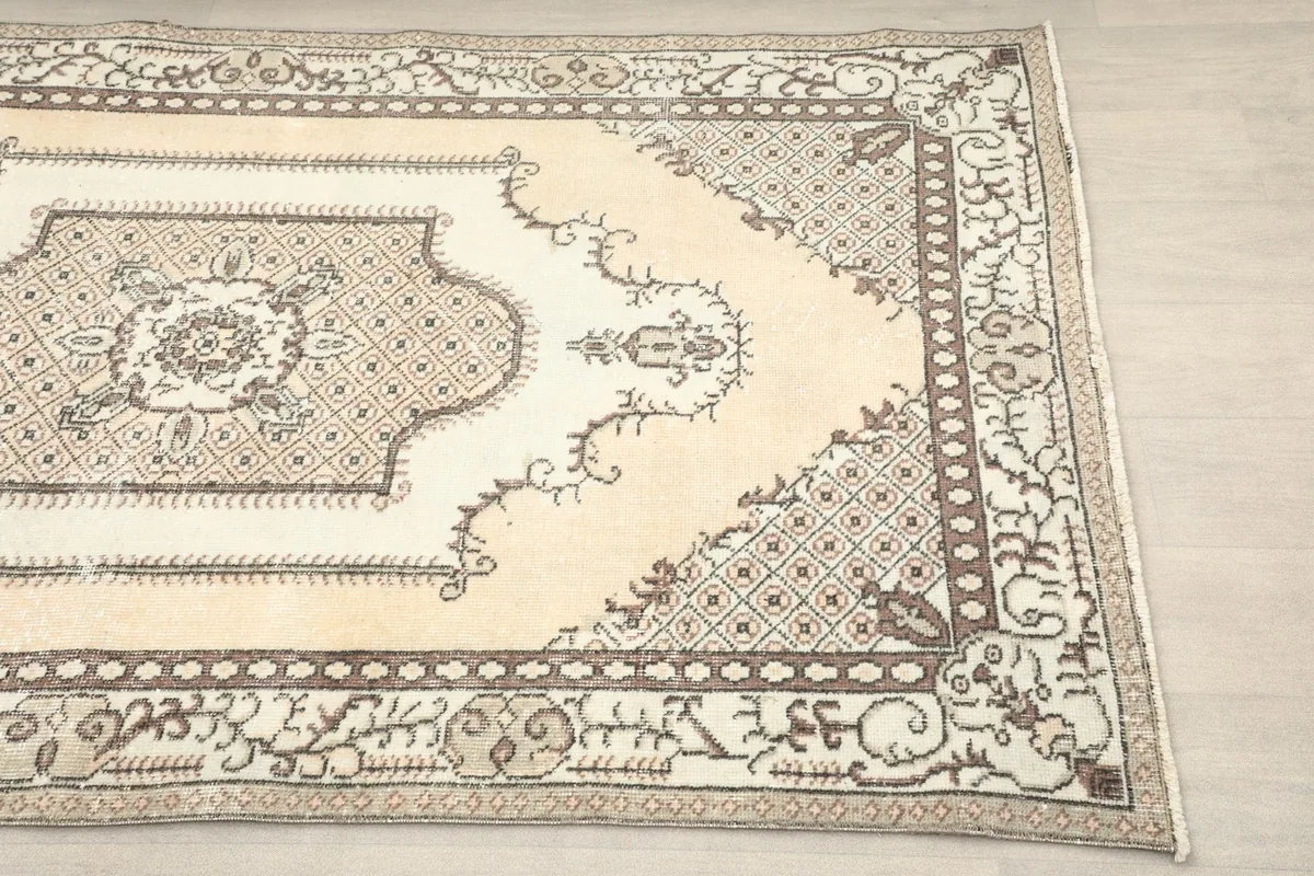 Close-up detail of the rug's corner showing the beige field and patterned border