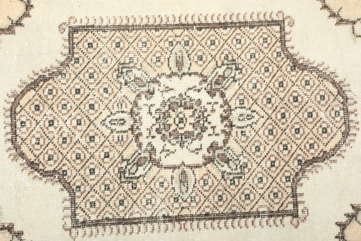Detailed view of the central medallion with its geometric and floral elements in brown and charcoal