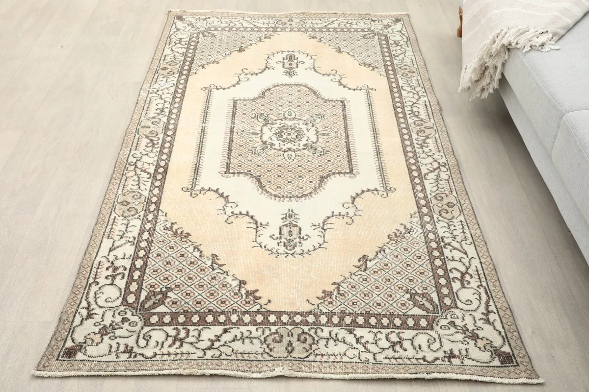Overhead view of the beige and ivory Anatolian rug placed on a light floor in a room setting