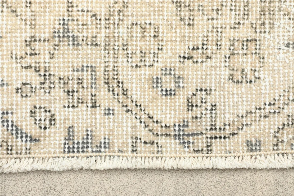Close-up detail of the hand-knotted wool pile and fringe on the vintage rug