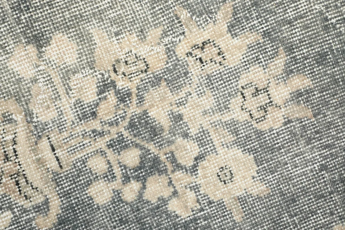 Texture of the low wool pile, showing faded gray and ivory colors and knotting