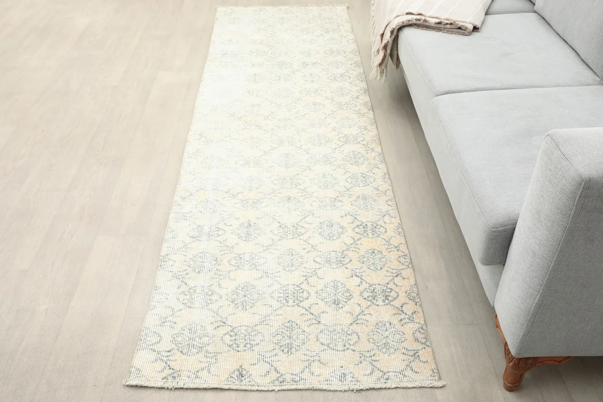 Runner rug placed in a living room setting next to a gray sofa, showing its full length and pattern.