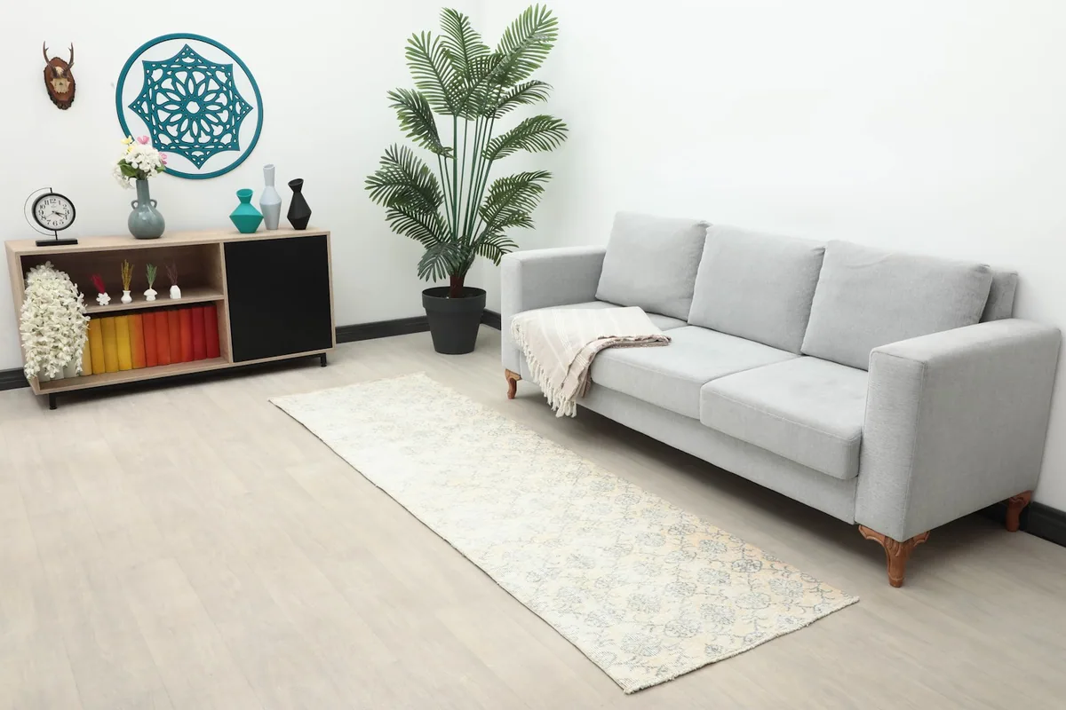 Wide shot of the cream and gray runner rug in a modern living space with a sofa and decor.