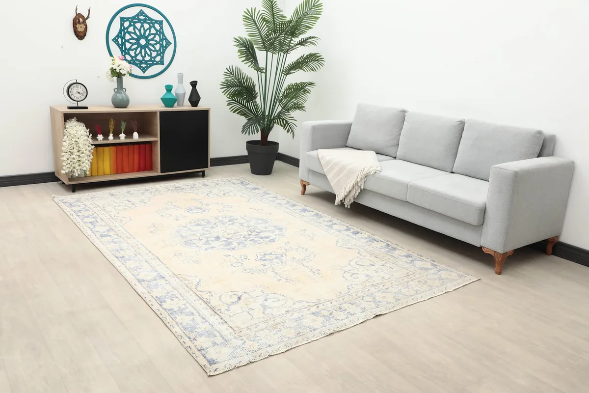 Angle view of the beige and blue vintage rug in a living space with a plant and sofa