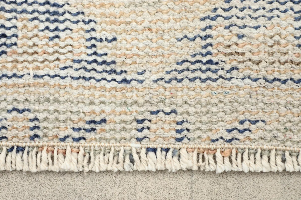 Close-up of the short fringe and the tightly woven edge of the vintage wool rug