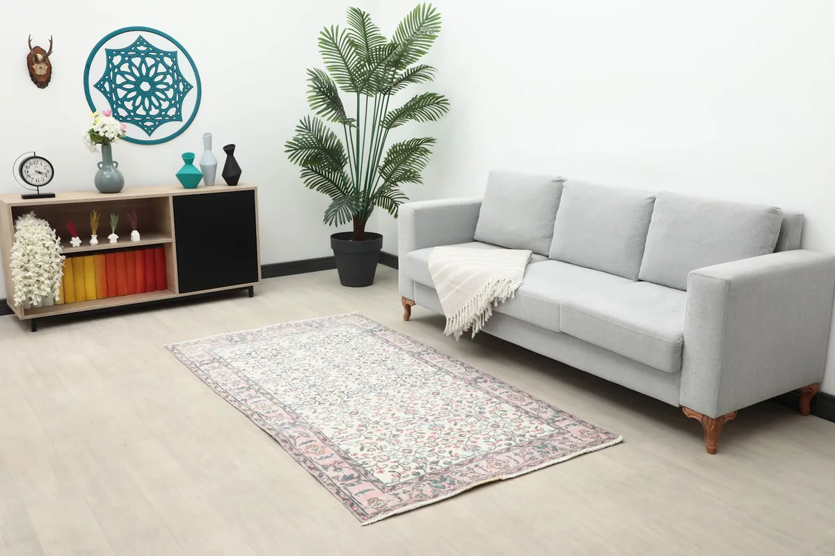 Vintage Anatolian rug in a living room setting with a light gray sofa and decorative cabinet