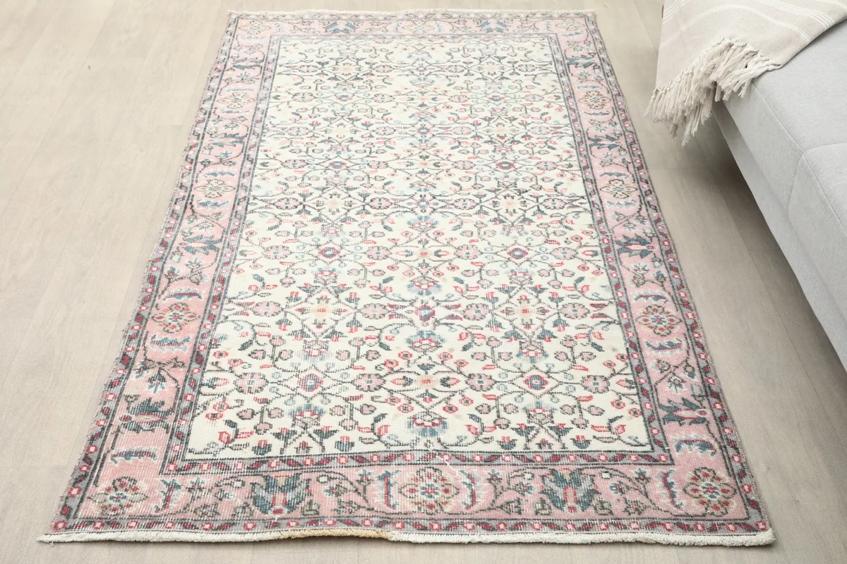 Overhead view of the ivory and rose vintage rug placed on a light wood floor