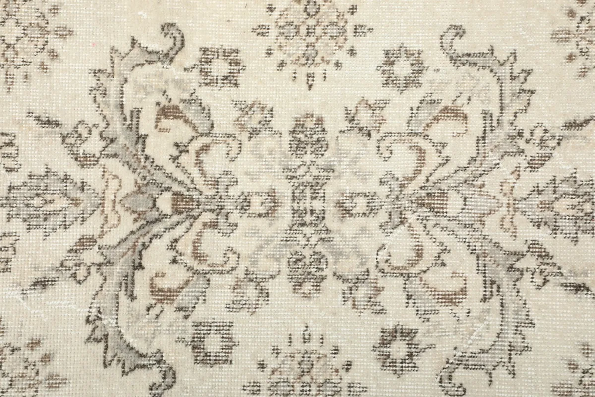 Close-up of the central medallion-like motif in gray on the ivory rug