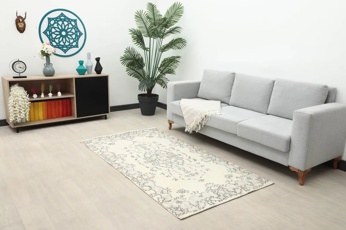 Wide shot of the small ivory and charcoal rug in a modern living room with a gray sofa and wooden cabinet.