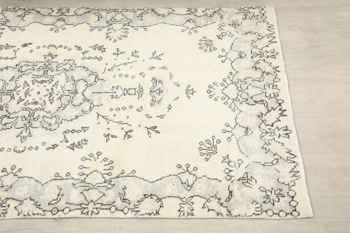Close-up detail of the corner and border design of the ivory and charcoal hand-knotted rug.
