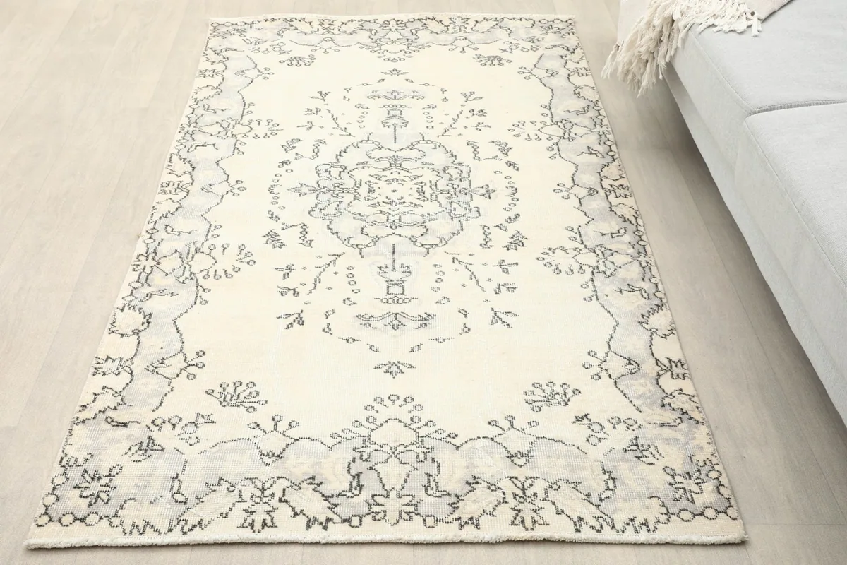 Overhead view of the ivory and charcoal medallion rug placed on a light wood floor in a room setting.