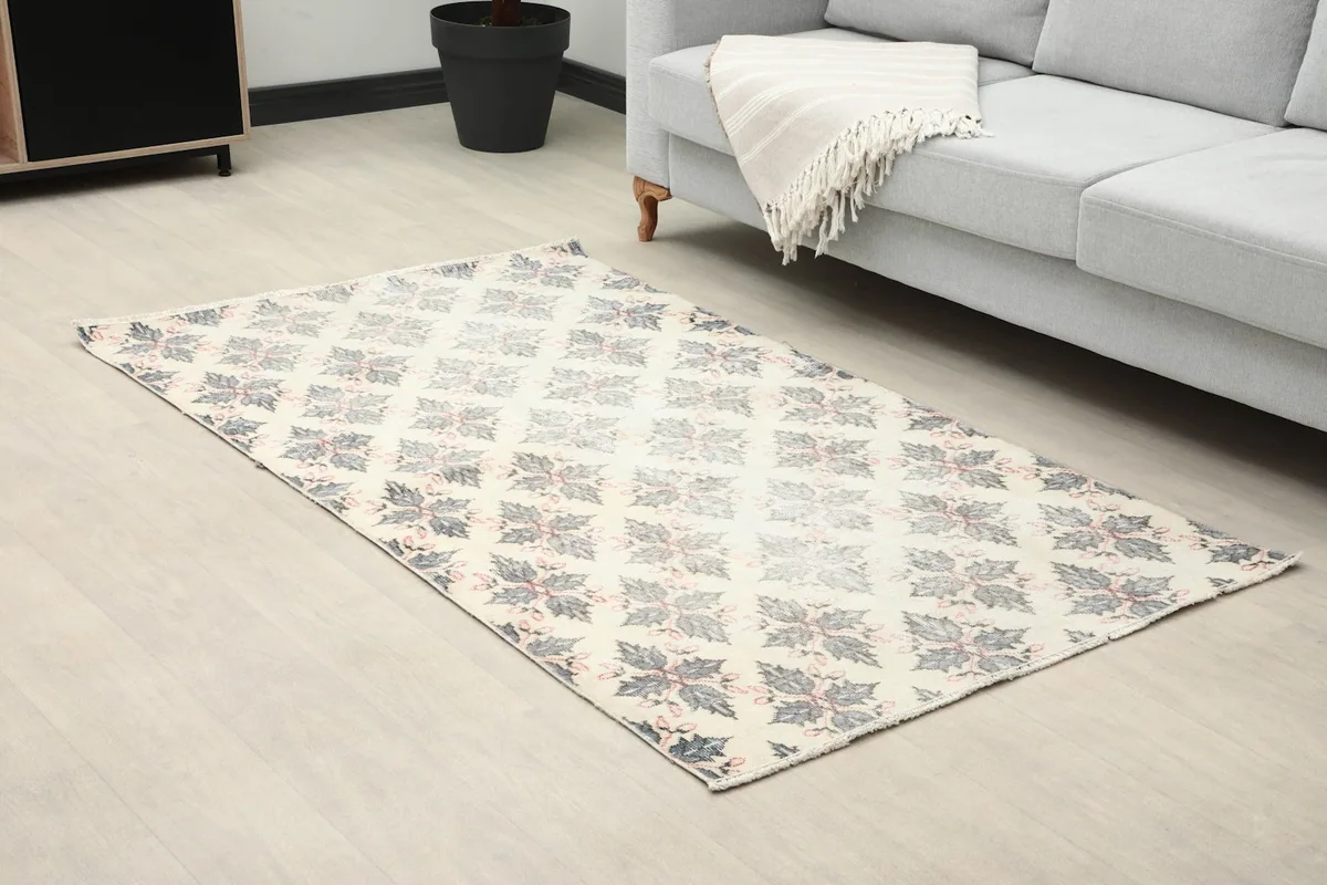 Close-up room view of the small area rug next to a gray sofa
