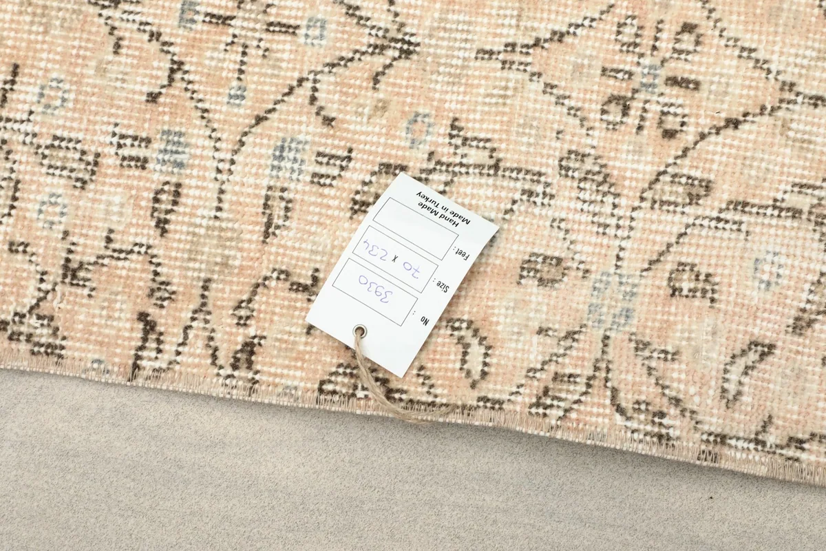 Close-up of the rug's surface with a tag, showing the intricate pattern and pile texture.