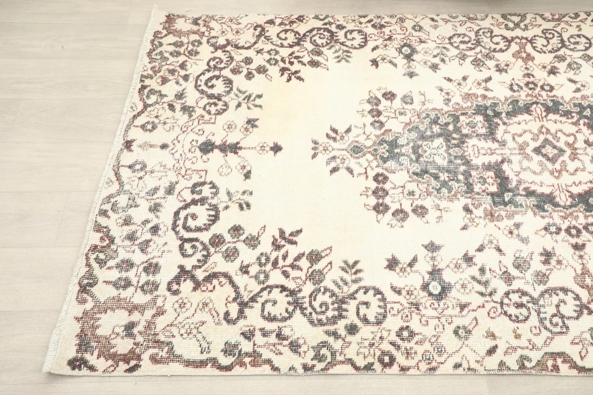 Detailed view of the rug's corner, showing the faded charcoal and rust patterns