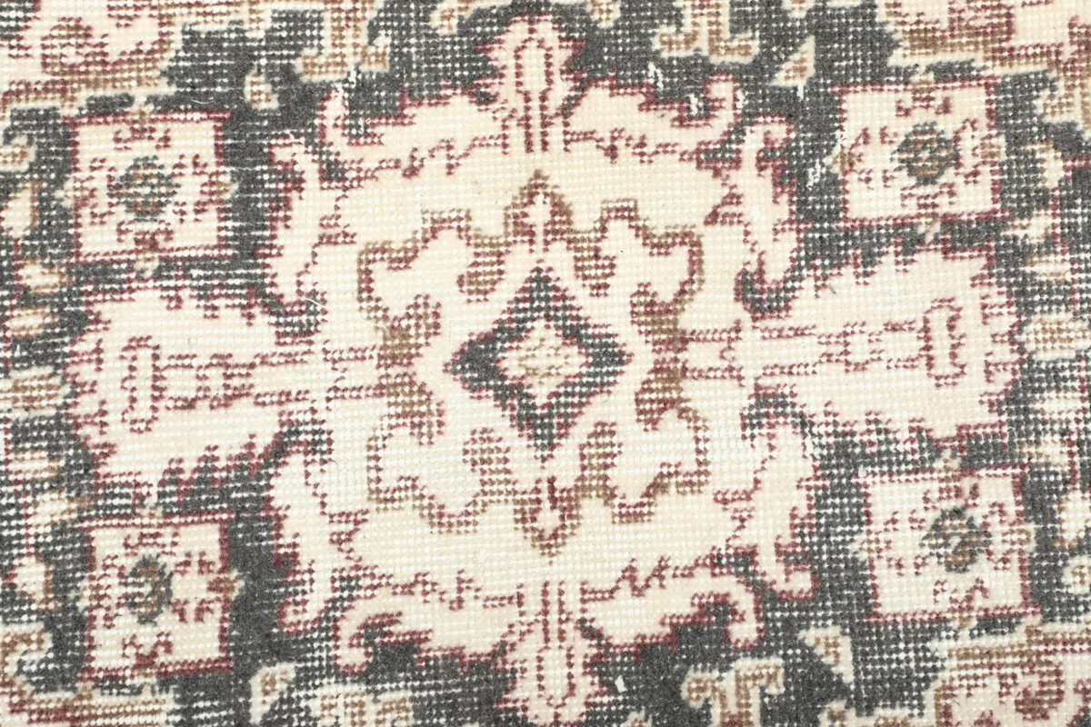 Macro detail of the hand-knotted wool pile and faded colors in the rug's pattern