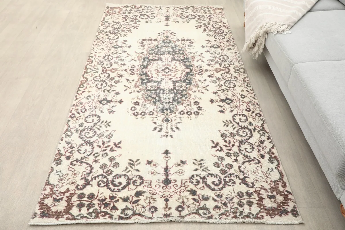 Overhead view of the ivory and charcoal rug on a light wooden floor next to a sofa