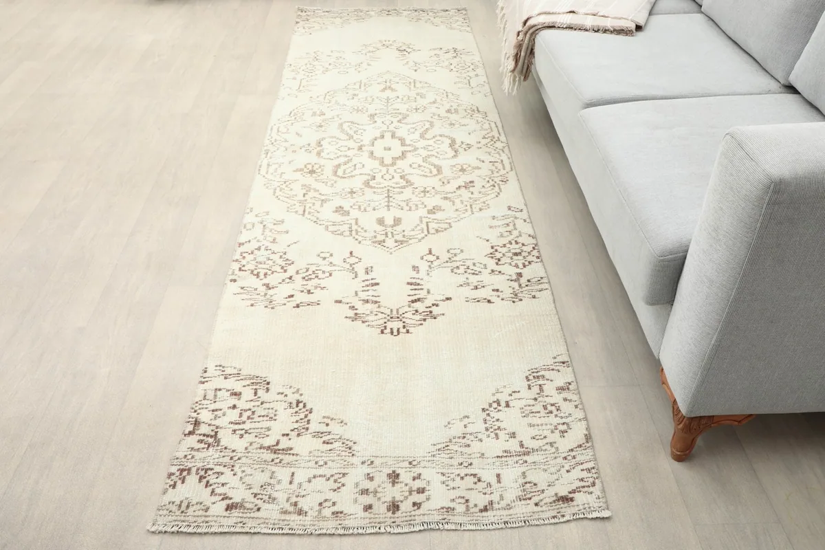 Runner rug placed in a living space next to a light gray sofa, showing its length and scale