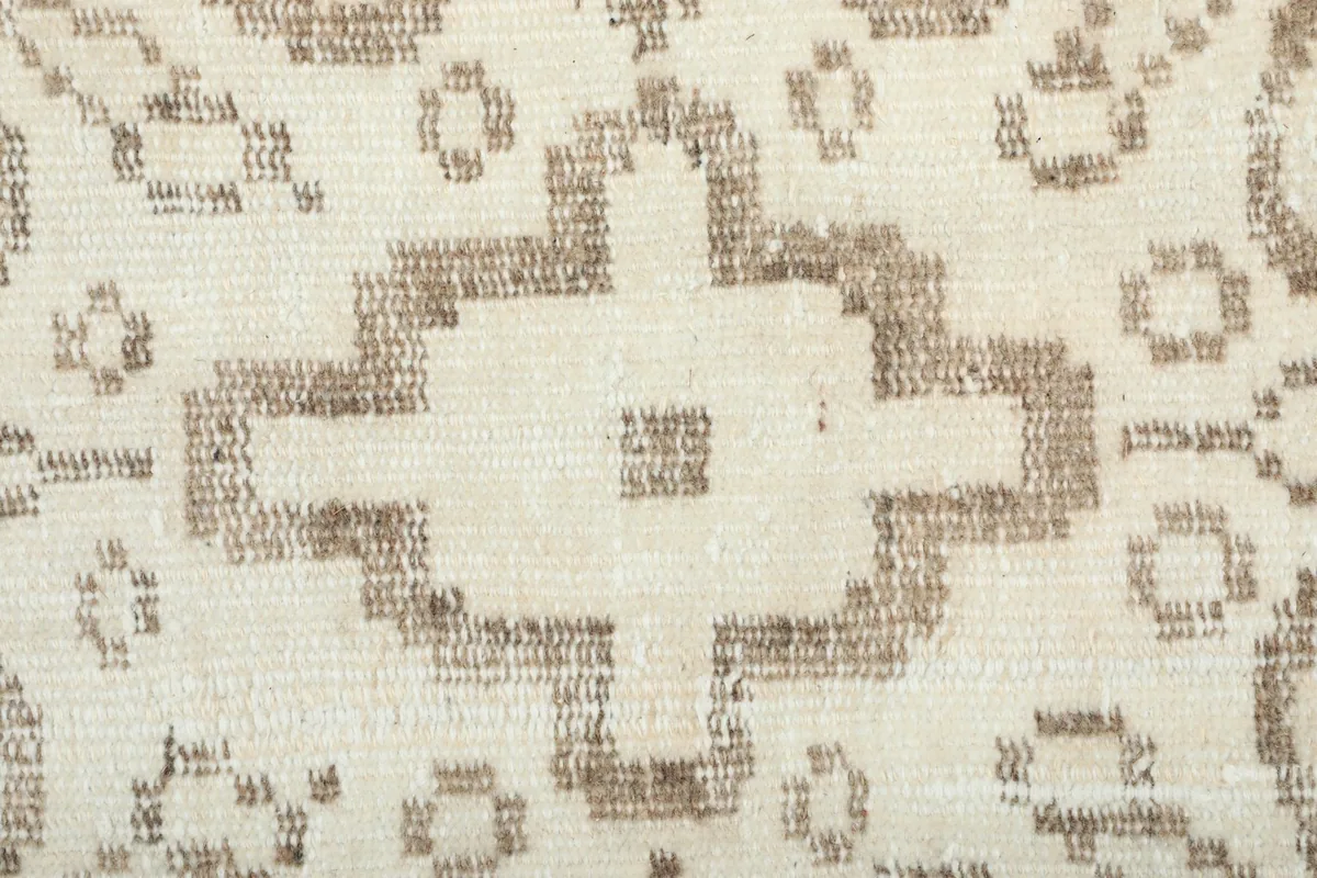 Very close view of the rug's pile, highlighting the texture and detail of the brown patterns on ivory
