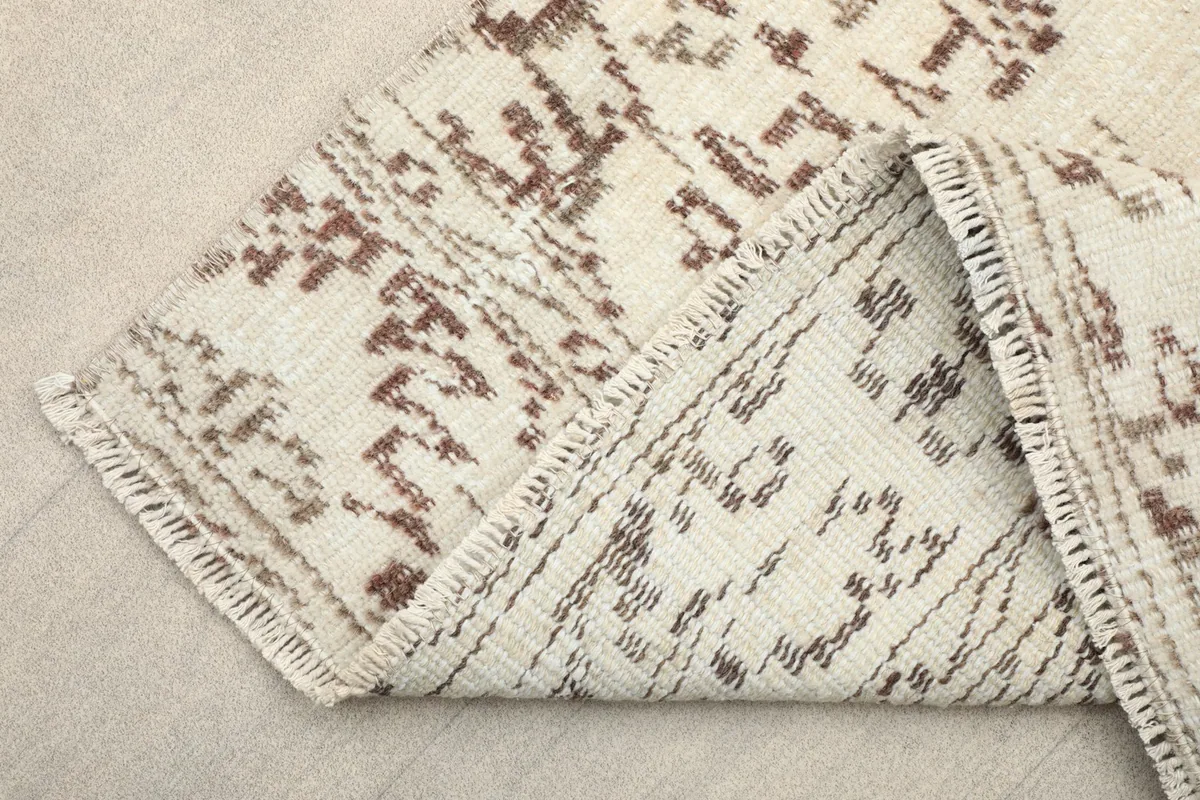 Folded corner of the rug revealing the backside, showing the cotton foundation and knotting