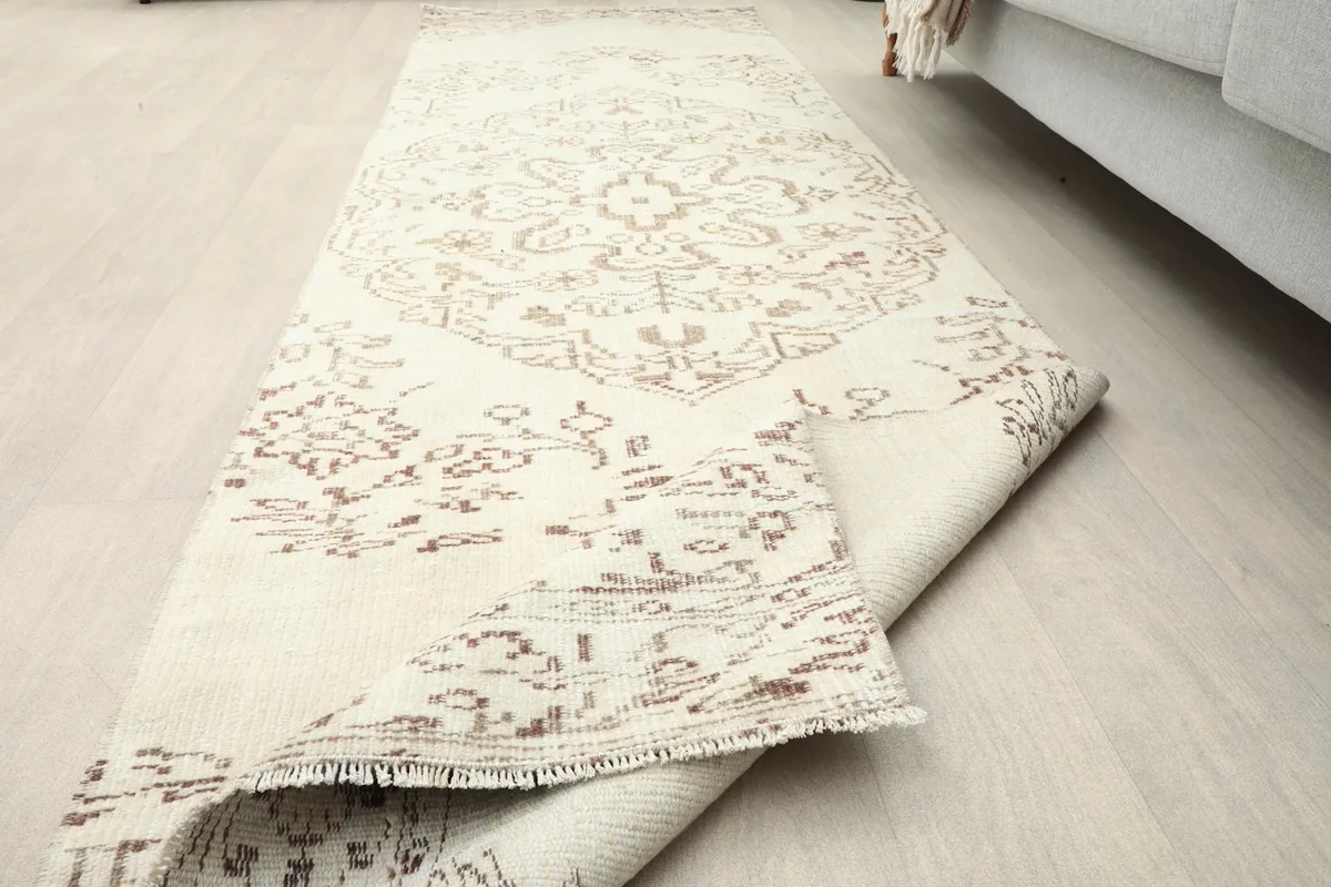 Runner rug with a corner folded back, showing its flexibility and thickness on the floor