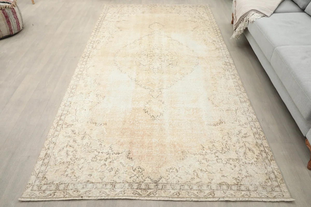 Cream vintage Anatolian rug in a living room setting with a light gray sofa