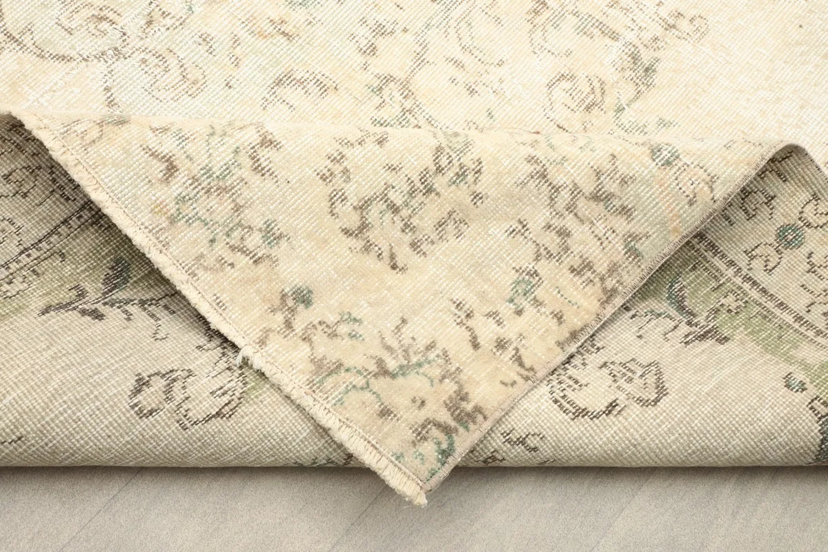 Folded corner showing the reverse side of the hand-knotted wool rug, revealing its cotton foundation.