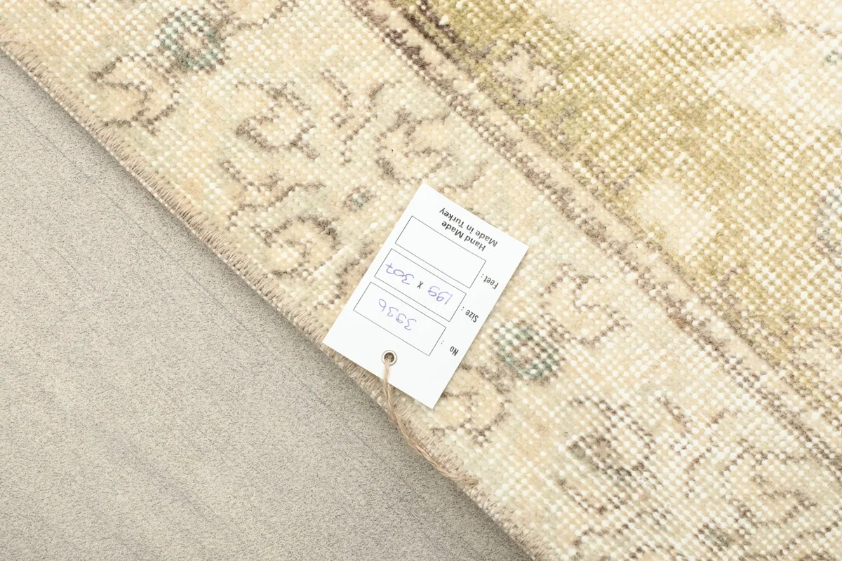 Rug corner with a product tag, showing the backing and edge of the hand-knotted construction.