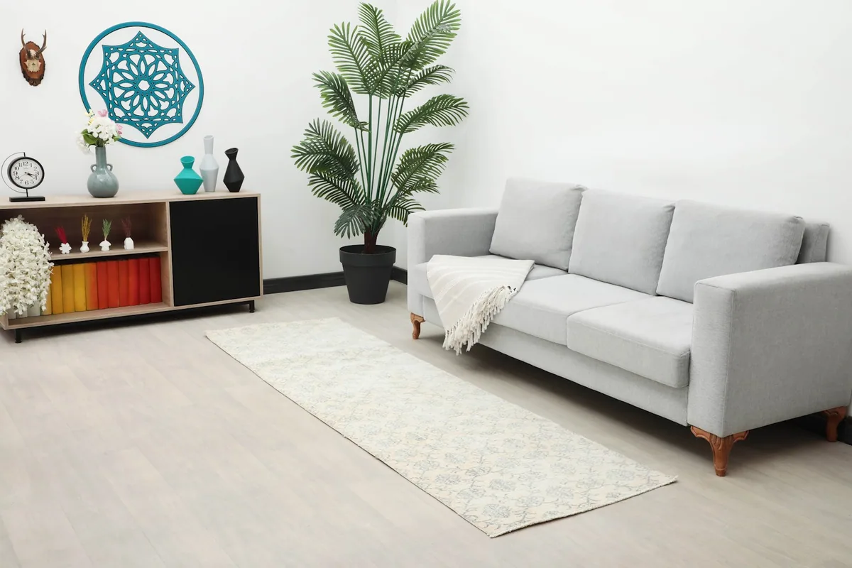 Long view of the ivory and blue runner rug in a living room setup with a light sofa and plant.
