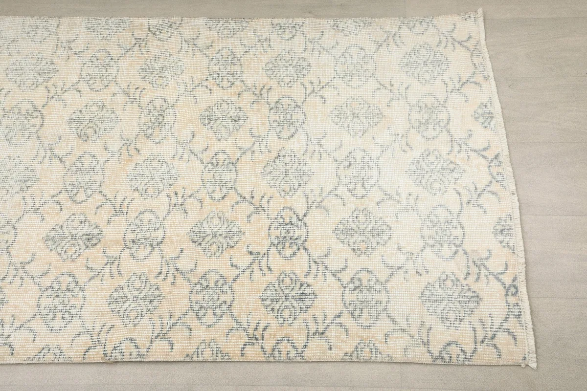 Close-up of the runner's pattern, showing the repeating faded blue floral and geometric motifs on an ivory field.