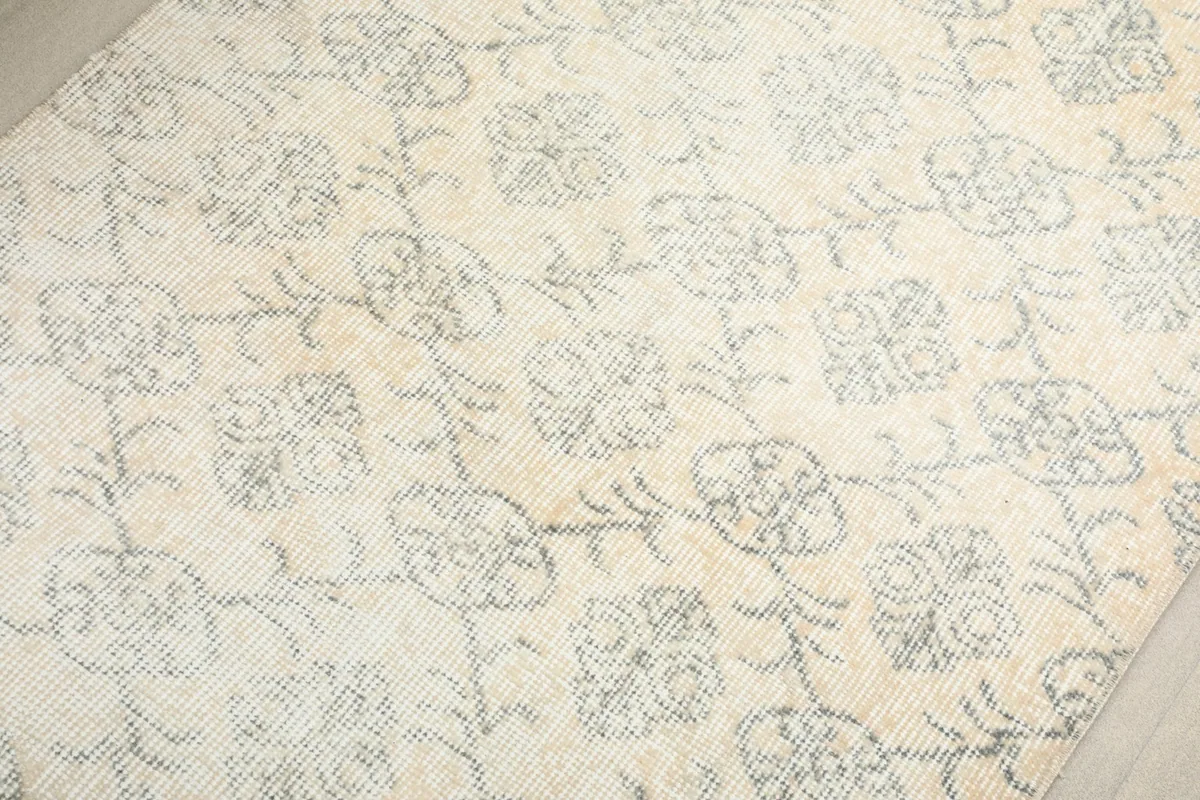 Close-up of the low pile and faded blue motifs against the ivory background, revealing the wool texture.