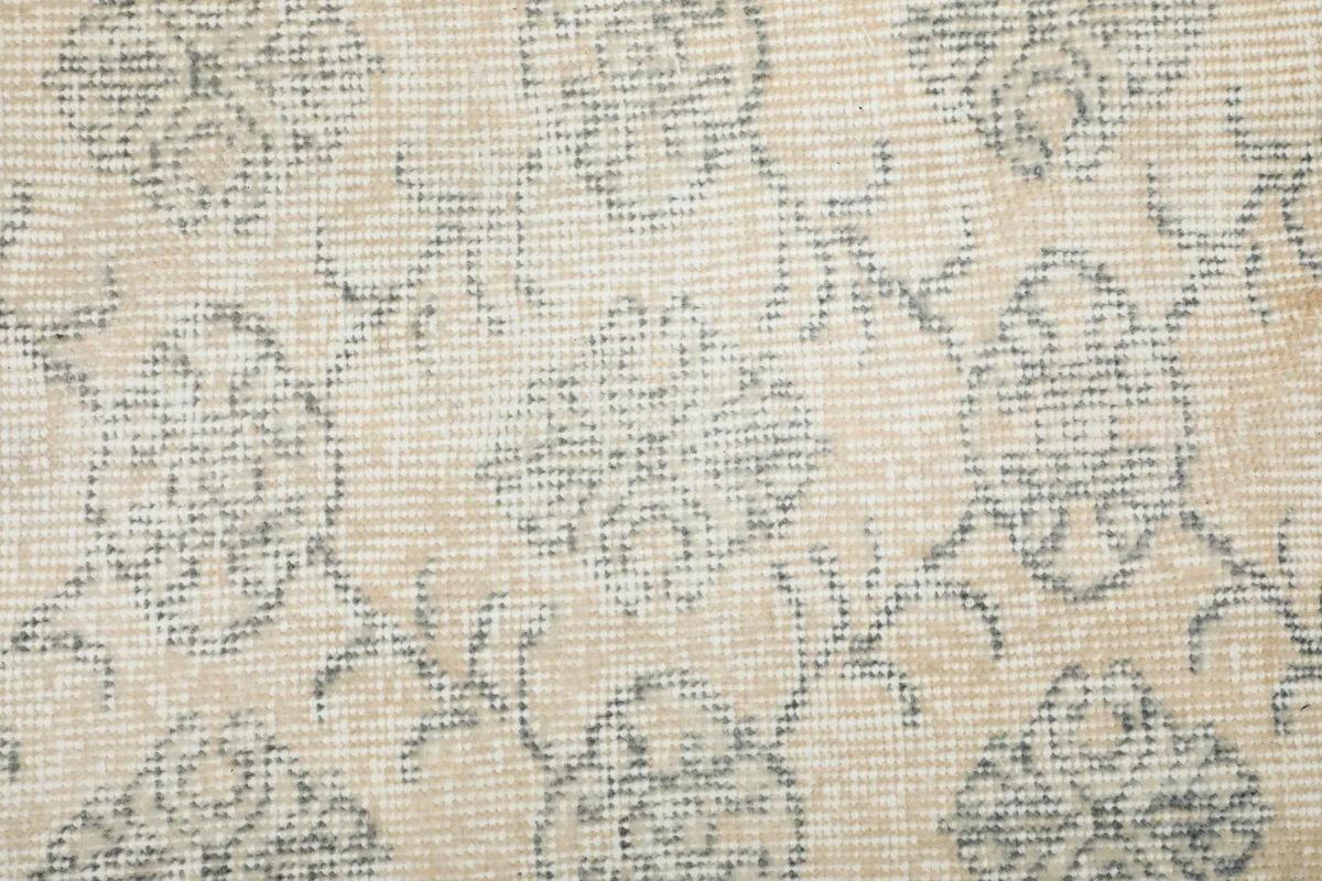 Macro view of the rug's low wool pile, showing the intricate knotting and the distressed appearance of the pattern.