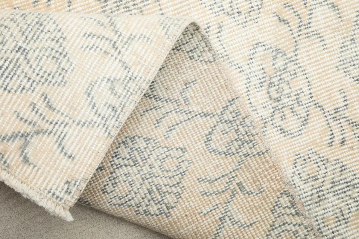 Detailed view of the rug's folded edge, revealing the wool pile and cotton foundation.