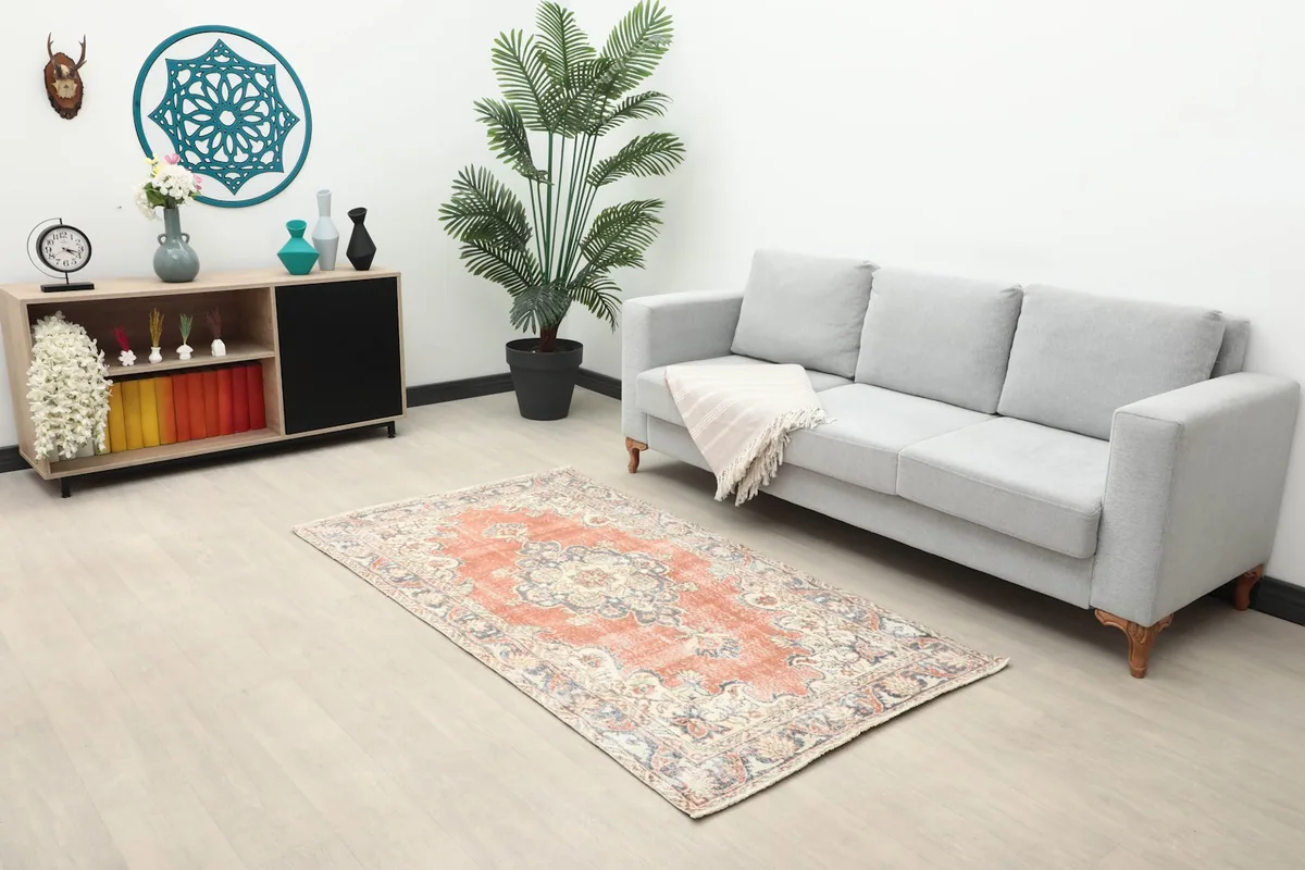 Rust area rug placed in a living room with a gray sofa and wooden cabinet