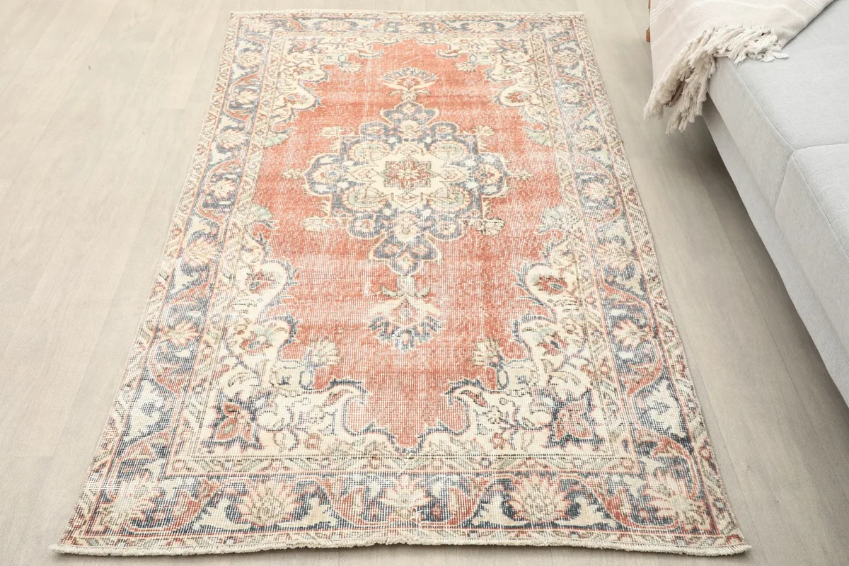 Top-down view of the rust vintage rug on a light wood floor in a room setting